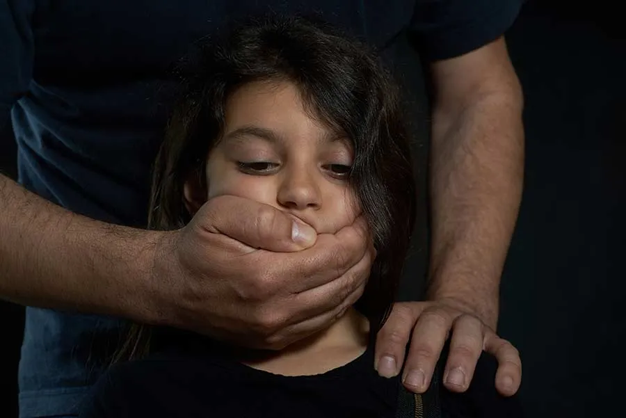 A man holding a girl's hand while covering her mouth with his hand.