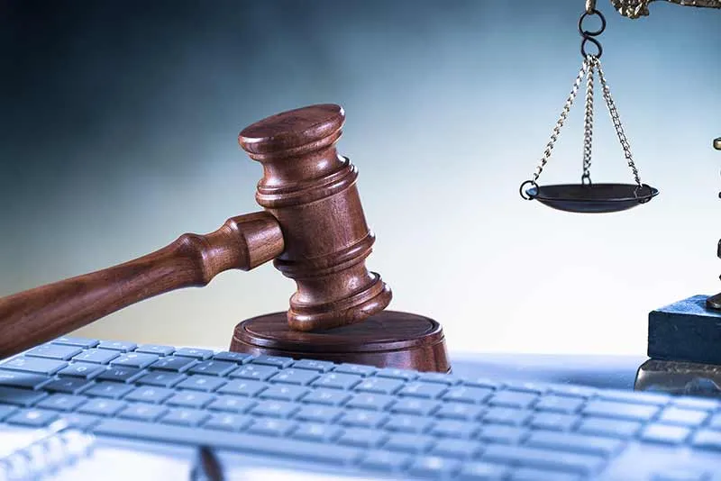 A gavel and scales on a keyboard - symbolizing justice and law in the digital age.