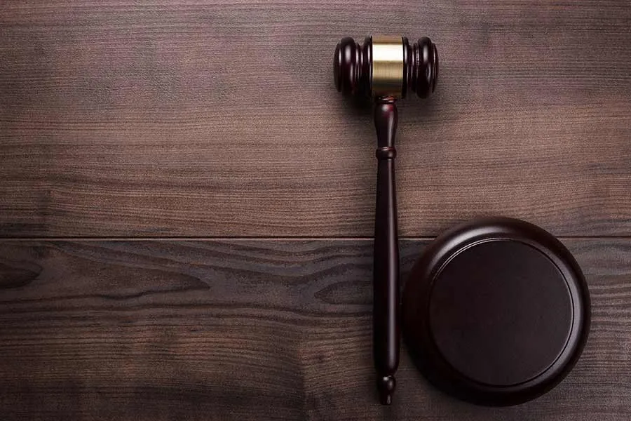 Wooden judge's gavel on table against wooden background.