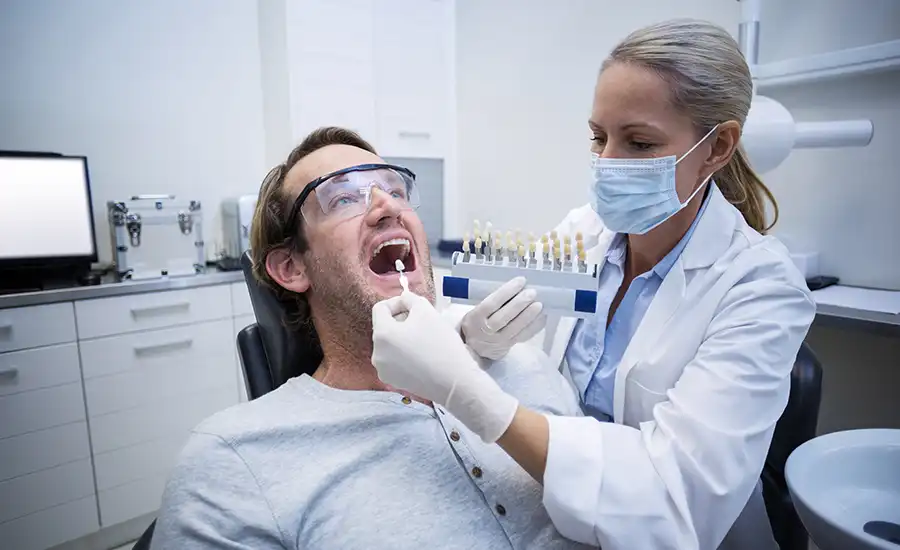 A dentist examining a man's teeth during a check-up.