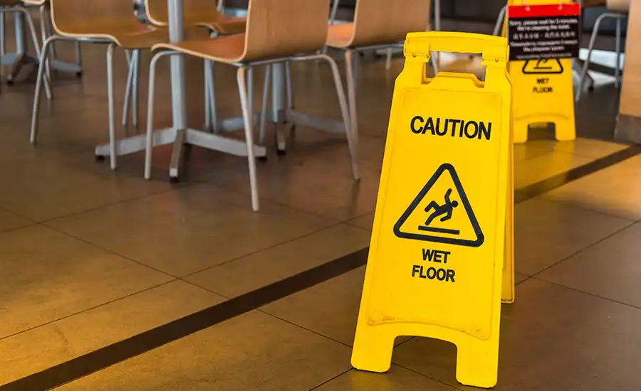 Caution: Wet floor sign in a restaurant, indicating potential slip hazards.