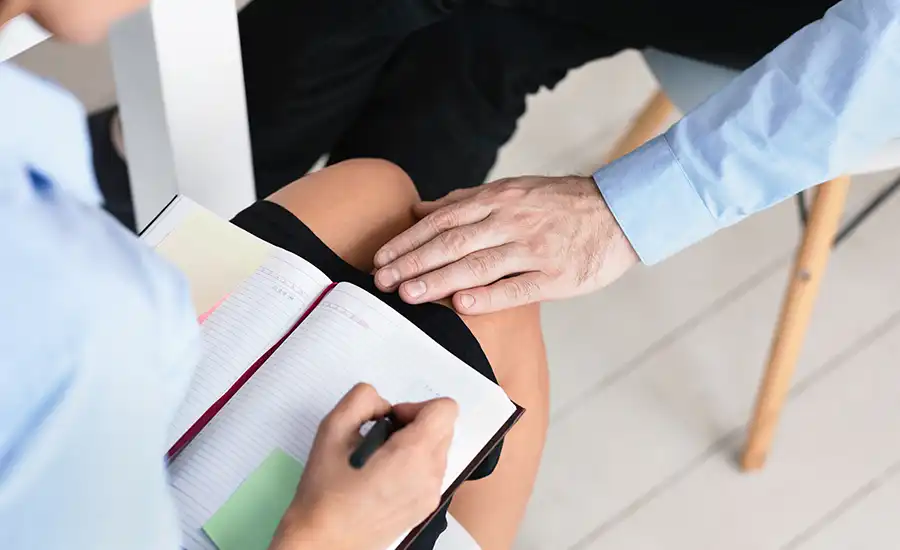 Image of a person at a desk with pen and paper, symbolizing teacher-sexual-abuse prevention.