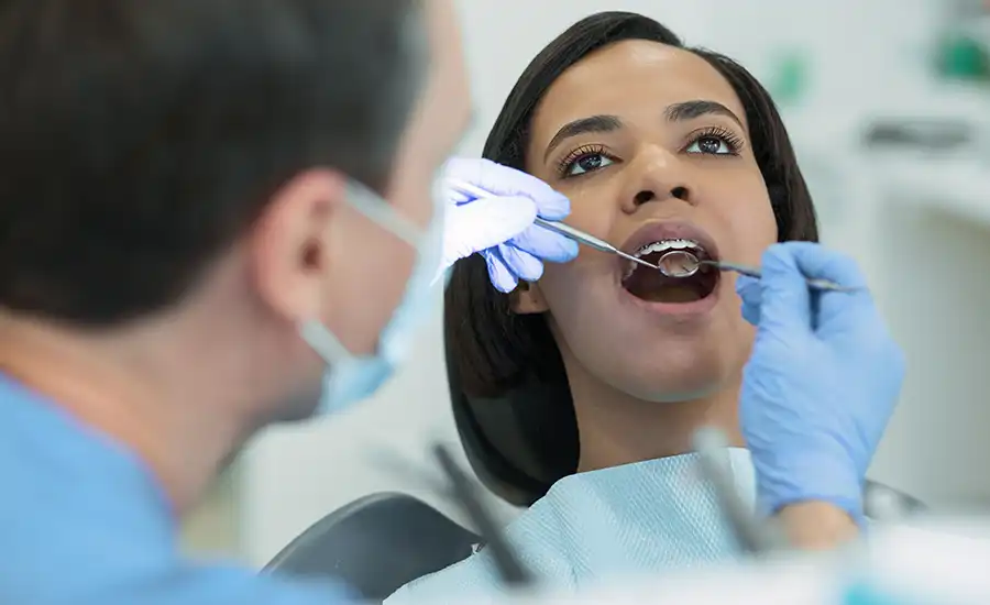 A dentist examining a woman's teeth for tooth decay during a routine check-up.