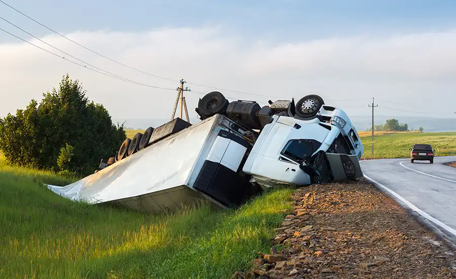 Truck flipped over on side of road.
