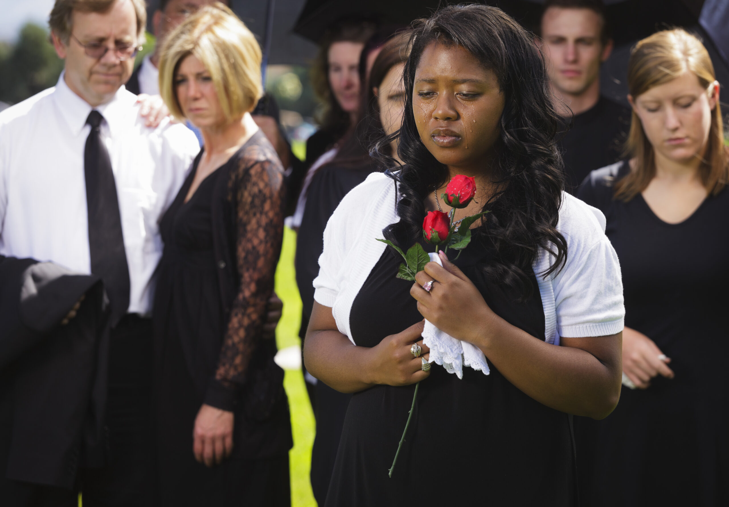 A grieving woman standing graveside at a funeral.